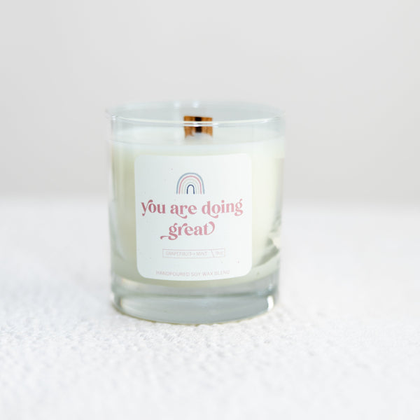 candle that says "you are doing great" with a rainbow