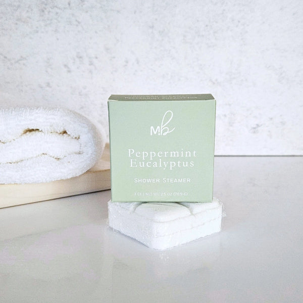 Peppermint Eucalyptus shower steamer packaging on a white surface with a towel in the background